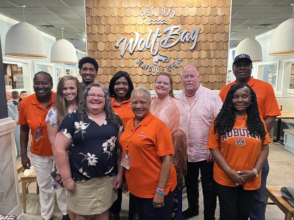 Auburn Housing Authority Staff and Commissioners are posed in front of a brick wall with text \'Wild Bay Seafood and Steak\'
