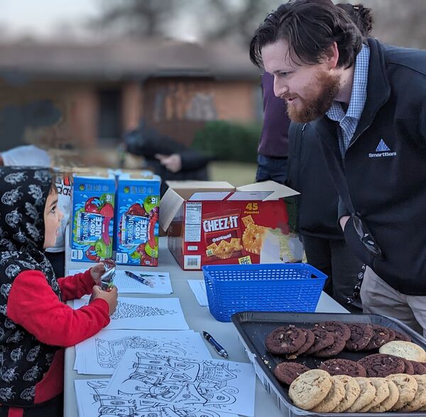 Auburn Smart Bank volunteer looking at a kid working on a coloring sheet