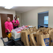 Volunteers with school supply bags on and boxes on table