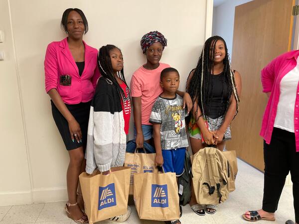 Mother with four kids posing with bags of school supplies