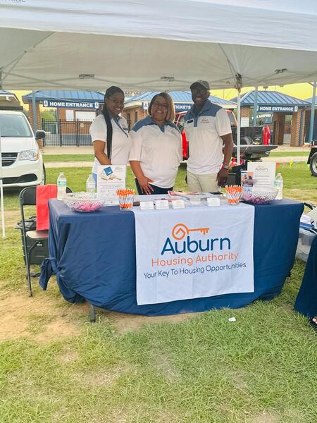 Auburn Housing Authority staff posed under tent behind their vendor table at National Night Out