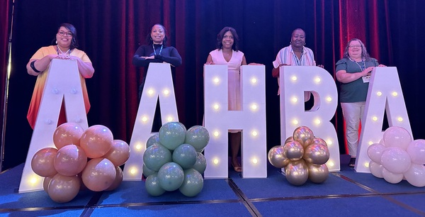 Staff and Commissioners behind tall AAHRA letters in lights with balloons 