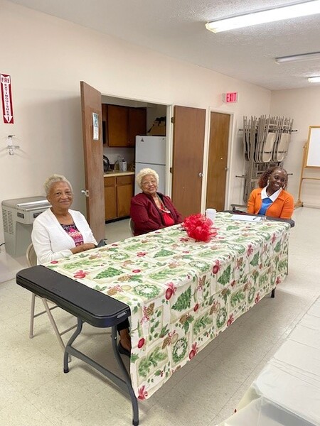 Three elderly women at the Christmas luncheon sitting around table